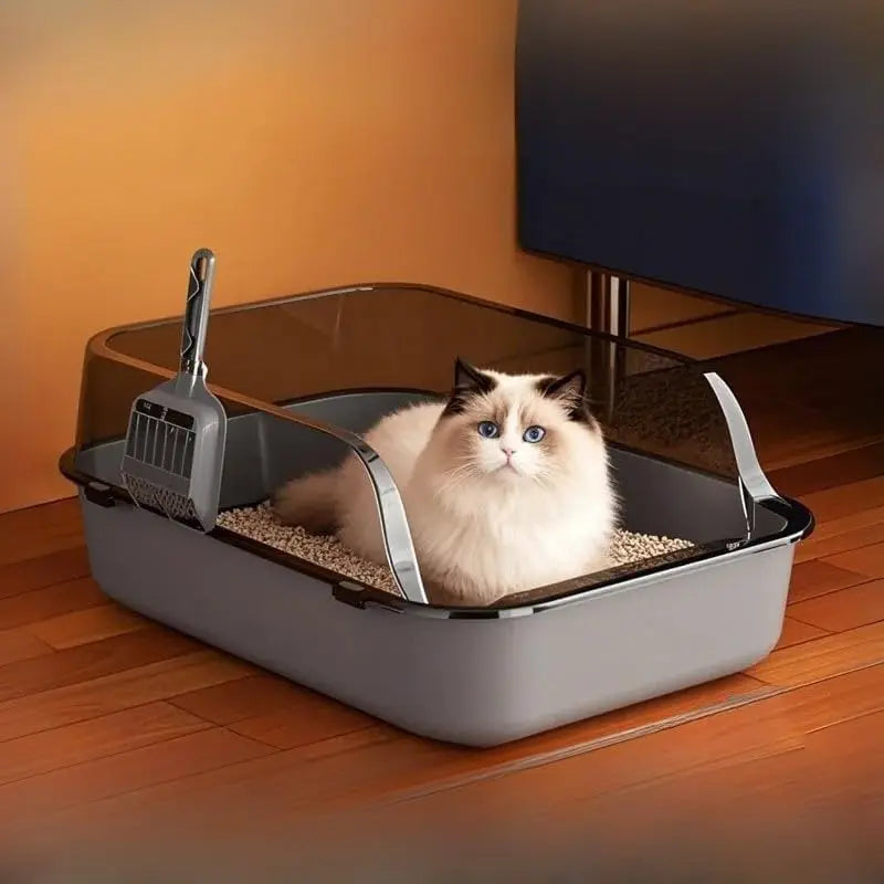 Gato blanco y gris dentro del arenero semicerrado, colocado en el salón de una casa