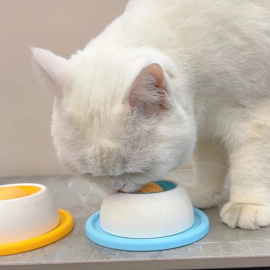 Gato comiendo del juguete de lameteo colocado en el suelo