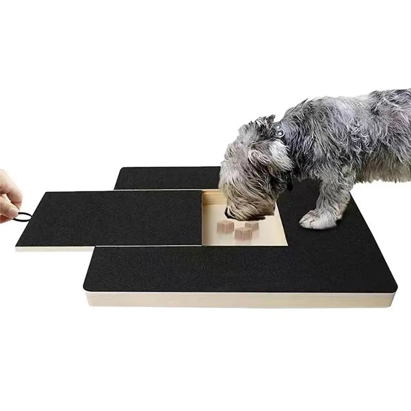 Perro gris cogiendo los premios de la cajita de la tabla rascadora mientras se lima las uñas