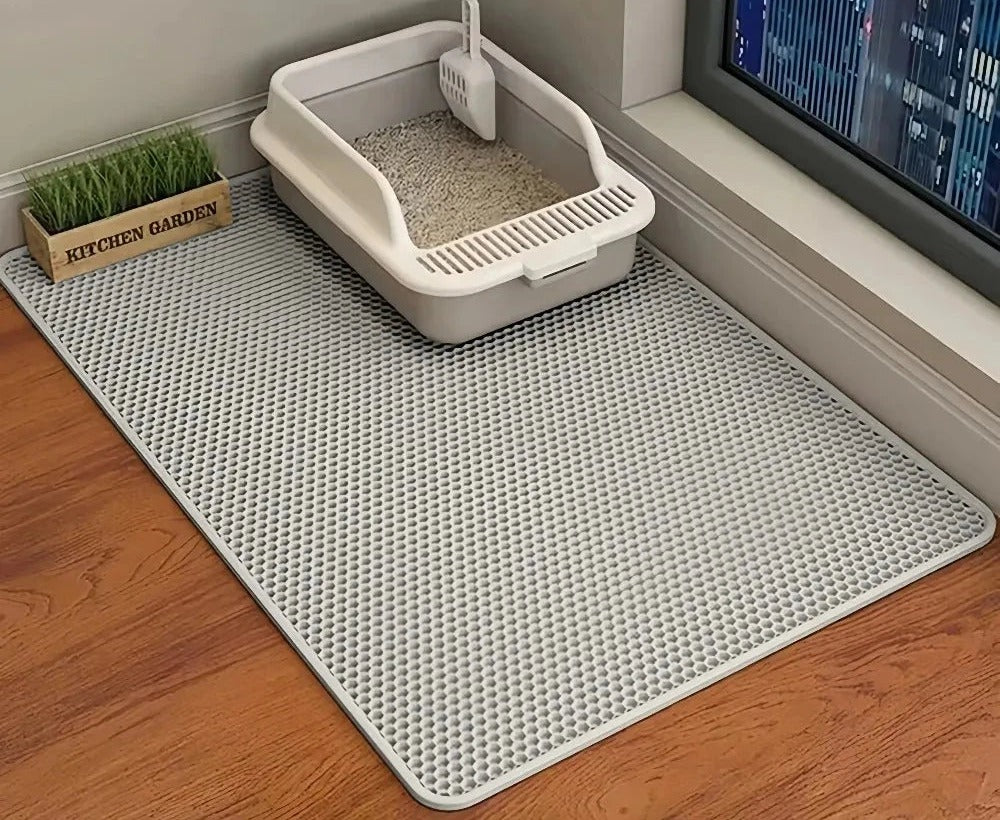Alfombra atrapa-arena bajo el arenero del gato, junto a la ventana y sobre suelo de madera