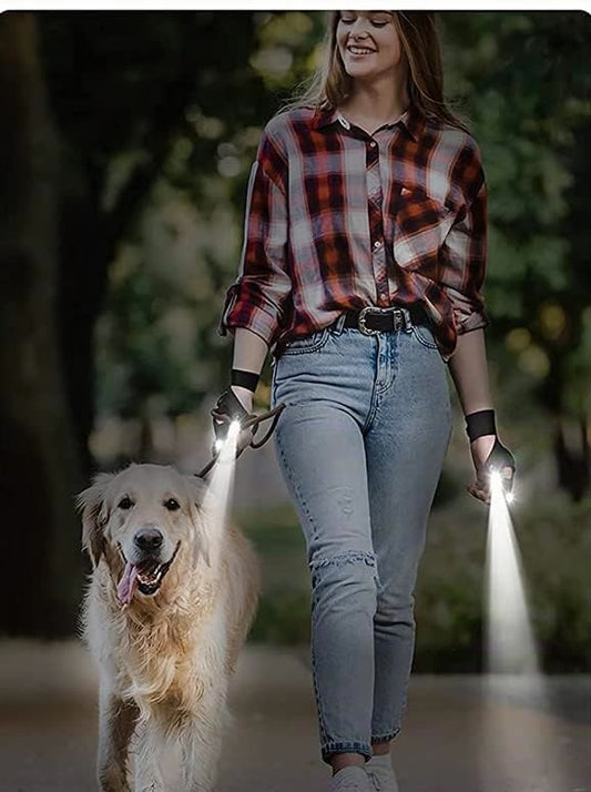 Mujer paseando a su golden de noche con los guantes LED encendidos