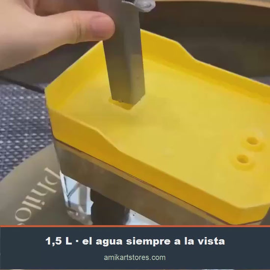 Un gato bebiendo del caño de la fuente, con el depósito transparente lleno de agua