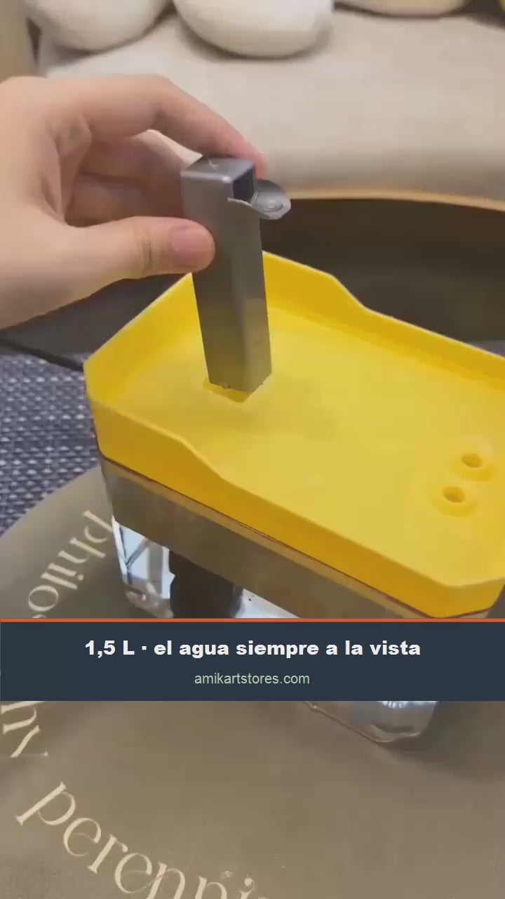 Un gato bebiendo del caño de la fuente, con el depósito transparente lleno de agua